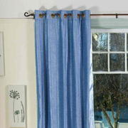 Light blue velvet grommet top curtains hung at a window