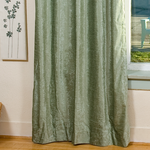 Olive green velvet grommet top curtains hung at a window