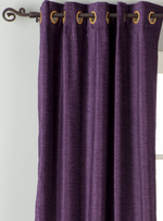 Purple velvet grommet top curtains hung at a window