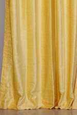 Yellow velvet grommet top curtains hung at a window