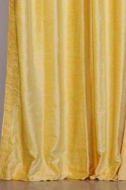 Yellow velvet grommet top curtains hung at a window