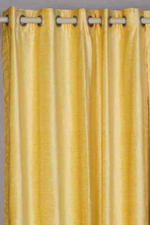 Yellow velvet grommet top curtains hung at a window