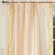 Golden sari tie top curtains hung at a window