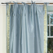 Gray sari tie top curtains hung at a window