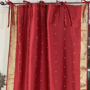 Maroon sari tie top curtains hung at a window