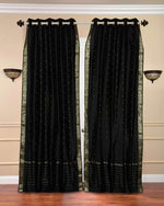 Black sari grommet top curtains hung at a window