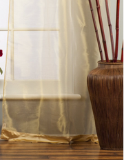 Golden sheer tissue tab top curtains hung at a window