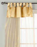 Golden sheer tissue tab top curtains hung at a window