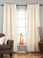 Cream raw silk rod pocket curtains hung at a window