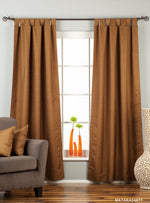 Brown raw silk tab top curtains hung at a window