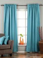 Turquoise raw silk rod pocket curtains hung at a window