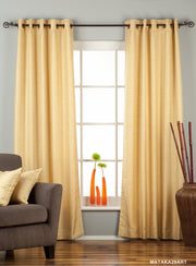 Golden raw silk grommet top curtains hung at a window