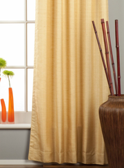 Golden raw silk grommet top curtains hung at a window