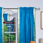 Turquoise sari rod pocket curtains hung at a window