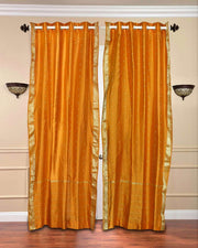 Mustard sari grommet top curtains hung at a window