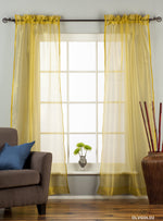 Gold sheer tissue rod pocket curtains hung at a window
