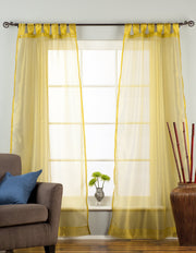 Gold sheer tissue tab top curtains hung at a window