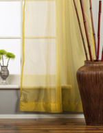 Gold sheer tissue rod pocket curtains hung at a window