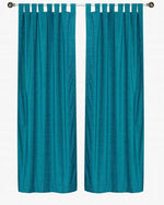 Turquoise velvet tab top curtains hung at a window