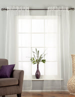 White sheer tissue rod pocket curtains hung at a window