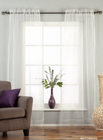 White sheer tissue rod pocket curtains hung at a window