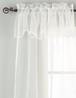 White sheer tissue rod pocket curtains hung at a window