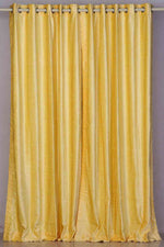 Yellow velvet grommet top curtains hung at a window