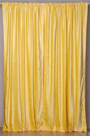 Yellow velvet rod pocket curtains hung at a window